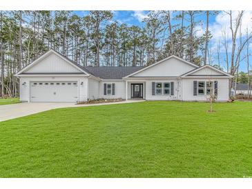 White house with gray shutters, two-car garage, and a well-maintained lawn at 121 Crossroad Dr. Nw, Calabash, SC 28467