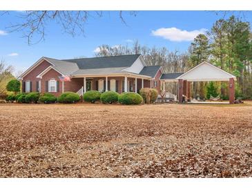 Brick home with covered porch and detached carport, surrounded by manicured landscaping at 3618 Highway 430, Nichols, SC 29581