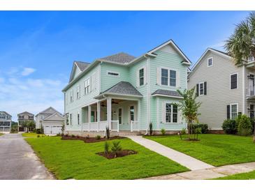 Two-story light green house with a front porch, landscaped yard, and walkway at 946 Crystal Water Way, Myrtle Beach, SC 29579