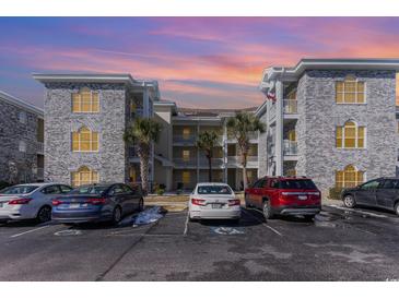 Gray brick condo building with parking and palm trees at 4705 Wild Iris Dr. # 105, Myrtle Beach, SC 29577