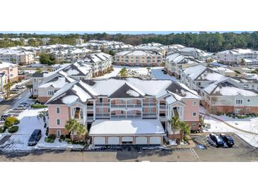 Aerial view of condo community showcasing snow-covered buildings, ample parking, and a pool at 4846 Carnation Circle # 203, Myrtle Beach, SC 29577