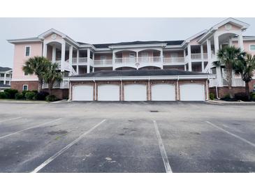 Three-story condo building featuring brick-based garages and pink siding at 4846 Carnation Circle # 203, Myrtle Beach, SC 29577