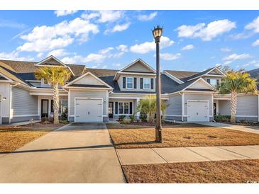 Charming townhome featuring a gray exterior, attached garage, and well-maintained landscaping under a bright blue sky at 626 Lorenzo Dr. # 626, North Myrtle Beach, SC 29582