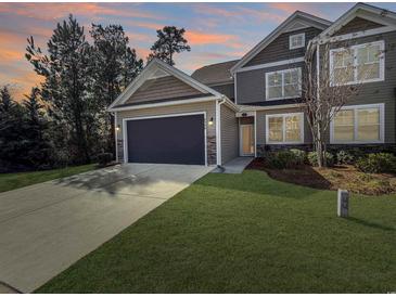 Two-story home with gray siding, a two-car garage, and a landscaped lawn at 220 Machrie Loop # A, Myrtle Beach, SC 29588