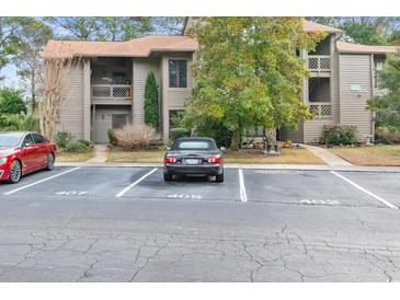 View of the building's exterior with parking, landscaping, and a well-maintained facade and car parked in parking space at 401 Indian Wells Ct. # 401, Murrells Inlet, SC 29576