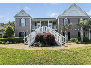 Inviting condo exterior with dual staircases, lush landscaping, and charming coastal architecture at 1109 Peace Pipe Ln. # 201, Myrtle Beach, SC 29579