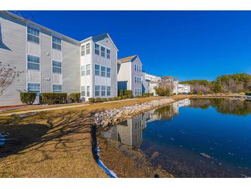 View of condo community with serene pond and manicured landscaping on a bright, sunny day at 2268 Essex Dr. # L, Surfside Beach, SC 29575