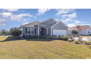 Gray house with landscaped lawn and water view at 7089 Shooting Star Way, Myrtle Beach, SC 29579