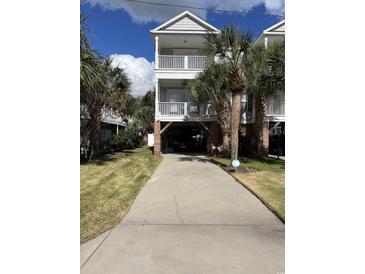 Inviting raised beach house with covered parking, palm trees, and multiple balconies at 114-A 11Th Ave. S, Surfside Beach, SC 29575