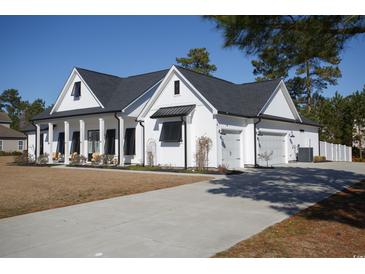 Charming white farmhouse with a gray roof, spacious driveway, and an attached two-car garage at 261 Marsh Tacky Loop, Myrtle Beach, SC 29588