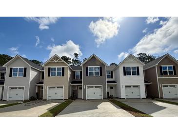View of newly constructed townhomes with gray siding, white trim, and single-car garages on a sunny day at 265 Christiana Ln. # D, Myrtle Beach, SC 29579