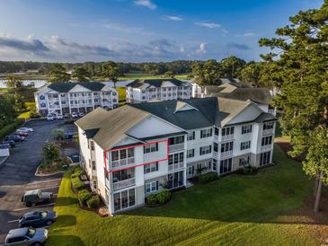 Low angle shows three story condo building with golf course, lake and trees behind it at 4459 Turtle Ln. # 3D, Little River, SC 29566