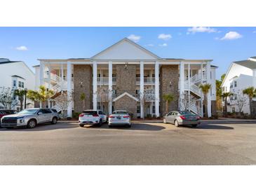 Three-story condo complex showing brick facade, white pillars and staircases on a sunny day at 136 Birch N Coppice Dr. # 11, Surfside Beach, SC 29575