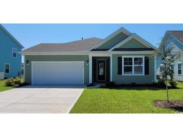 Charming green house with a white garage door and landscaped lawn at 1844 Hardwood Ct., Conway, SC 29526