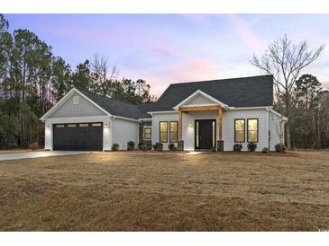 Stunning farmhouse exterior boasts a gray and white color scheme, two-car garage, and welcoming front porch at 270 Russ Rd., Loris, SC 29569