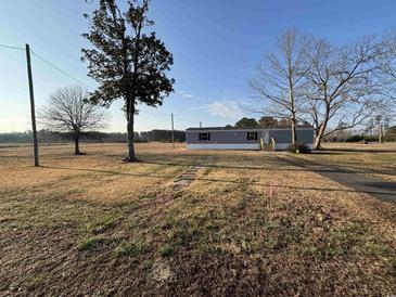 A charming home with a light gray exterior surrounded by open fields and a stone path to the front entrance at 6461 Norton Rd., Green Sea, SC 29545