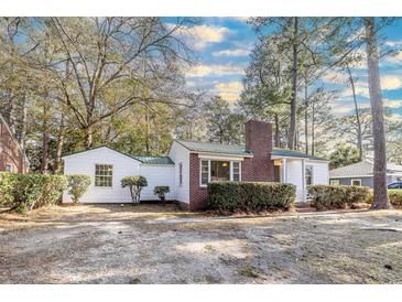 Charming home featuring white siding, brick chimney, green metal roof, and mature landscaping at 2505 Redwood St., Georgetown, SC 29440
