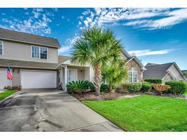 Charming home exterior with well-manicured lawn and landscaping, complemented by a stone facade and a white garage door at 4225 Rivergate Ln., Little River, SC 29566