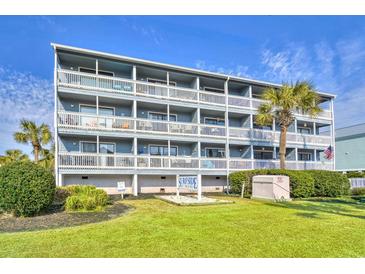 Four-story condo building with white railings and palm trees on a sunny day at 1210 N Ocean Blvd. # 202, Surfside Beach, SC 29575
