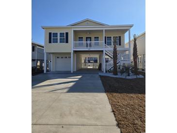 Charming elevated beach house with a spacious driveway, lush landscaping, and a two-story porch at 328 46Th Ave. N, North Myrtle Beach, SC 29582