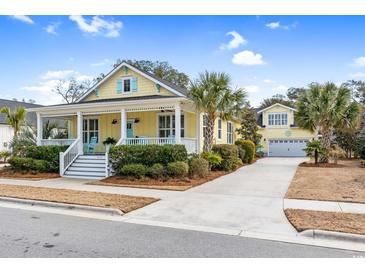 Charming yellow home featuring a welcoming front porch, a spacious driveway, and a detached garage at 6514 Anchors Bend Dr Sw, Ocean Isle Beach, NC 28469