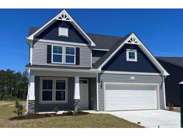 Beautiful two-story home with a two car garage and gray siding against a blue sky at 1111 Forest Bend Dr., Calabash, NC 28467