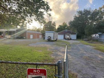 Property with a grassy yard, multiple outbuildings, and a driveway at 127 Nu-Shell St, Georgetown, SC 29440