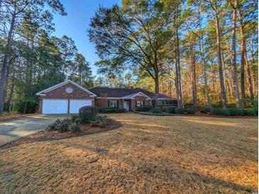 Charming brick home featuring an attached two-car garage, lush landscaping, and mature trees at 270 Georgetown Dr., Pawleys Island, SC 29585