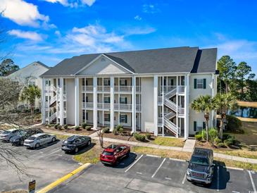 Three-story condo building with white columns, green shutters, and ample parking under a bright sky at 5070 Windsor Green Way # 204, Myrtle Beach, SC 29579