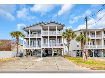 Inviting two-story beach house with spacious balconies, gray siding, and palm trees in a coastal setting at 624-B Seabreeze Dr., Garden City Beach, SC 29576