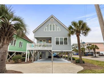 Charming raised beach house with light gray siding, white trim and a spacious open carport and lush palm trees at 1032 N Ocean Blvd., Surfside Beach, SC 29575