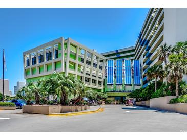 View of the Coral Beach Resort entrance with palm trees and a well-maintained, colorful facade against a bright blue sky at 1105 S Ocean Blvd. # 732, Myrtle Beach, SC 29577