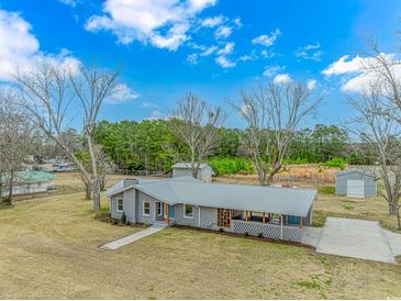 Well-maintained home featuring grey brick and metal roof, nestled on a spacious lot with mature trees at 2360 Highway 701 North, Loris, SC 29569