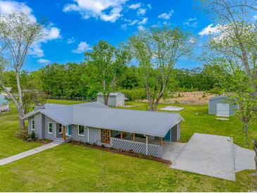 An exterior aerial view of a charming gray brick home with a large green yard and metal roof at 2360 Highway 701 North, Loris, SC 29569