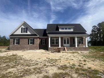 New brick home featuring a welcoming front porch with white columns and a classic, symmetrical design under a bright sky at 713 Horry Rd., Conway, SC 29526