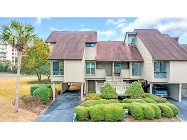 Charming exterior view of a tan home featuring neat landscaping and covered parking at 163 Heron Marsh Dr. # 61, Pawleys Island, SC 29585