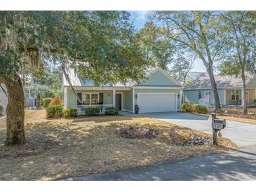 Charming home with a well-manicured front yard, a white picket fence, and an attached two-car garage at 182 Minnow Dr., Pawleys Island, SC 29585