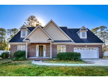 Charming, red brick two-story home featuring dormer windows, a two-car garage, and well-maintained landscaping at 221 Hagley Dr., Pawleys Island, SC 29585