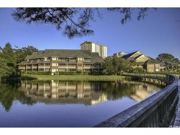 Scenic waterfront condo complex with lush landscaping and bridge reflected in the water at 410 Melrose Pl. # 304, Myrtle Beach, SC 29572