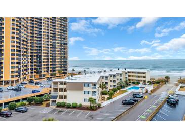 Exterior view of the condo and parking lot near the ocean with clear blue skies at 9620 Shore Dr. # C101, Myrtle Beach, SC 29572