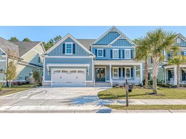 Charming two-story home featuring a blue exterior, a two-car garage, and a well-manicured front yard at 1054 East Isle Of Palms Ave., Myrtle Beach, SC 29579