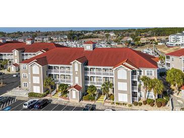 Beautiful condo building with red roof, beige siding, and white balconies overlooking the marina at 4220 Coquina Harbour Dr. # B-12, Little River, SC 29566