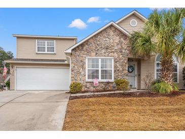 Charming two-story home with stone accents, a well-manicured lawn, and attached garage at 4309 River Gate Ln., Little River, SC 29566