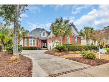 Beautiful red brick home featuring a well-manicured front yard with palm trees and circular driveway at 602 Sea Vista Ln., North Myrtle Beach, SC 29582