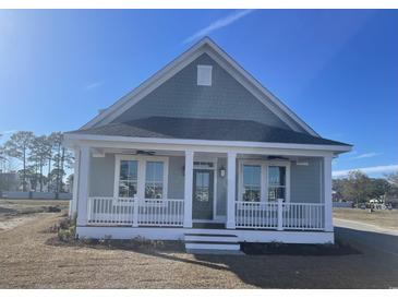 Charming, light blue, single-story home featuring a welcoming front porch and beautiful architectural details at 8125 Living Tide Dr., Myrtle Beach, SC 29572