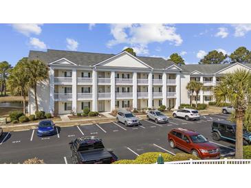 Exterior view of three story condo complex with ample parking spaces and manicured greenery at 5060 Windsor Green Way # 304, Myrtle Beach, SC 29579