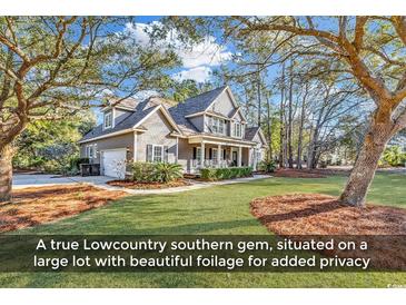 Charming two-story home with mature landscaping, inviting front porch with rocking chairs, and well-manicured lawn at 52 Olde Canal Loop, Pawleys Island, SC 29585