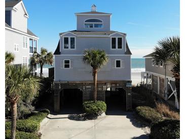 Beach house on stilts with a view of the ocean and palm trees, featuring a ground-level covered parking area at 547 South Waccamaw Dr., Garden City Beach, SC 29576