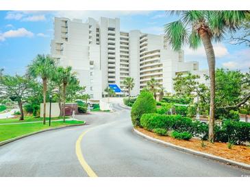 Beautiful exterior shot of a condo building with palm trees and a winding road leading up to the entrance at 101 Ocean Creek Dr. # Jj-1, Myrtle Beach, SC 29572