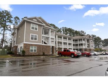 Apartment building featuring multiple balconies, stone accents, and ample parking on a partially cloudy day at 125 South Shore Blvd. # 201, Longs, SC 29568